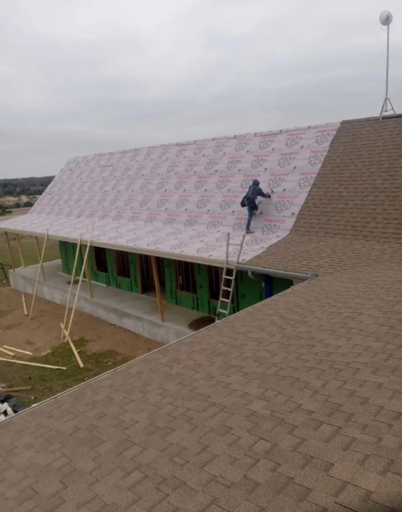 Worker preparing underlayment for a metal roof installation in Reminderville